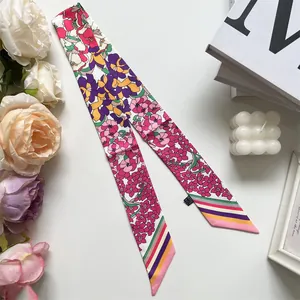 Macro detail of twilly silk scarf with floral patterns and striped ends on a white desk