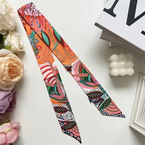 Detail of tropical floral satin hair scarf with orange base and lush green leaf patterns