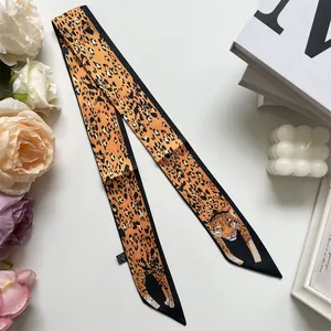 Detail of orange leopard print twilly scarf with cheetah head motifs on silk-like fabric
