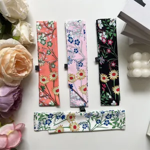 Flat lay of thin floral silk scarves in peach, pink, black, and white colors with floral print