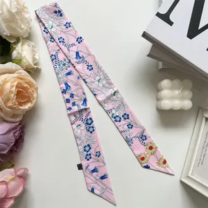 Close-up of pink floral twilly scarf with 100% polyester label on white desk