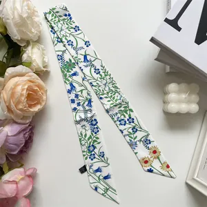 Close-up of a floral skinny silk scarf with blue and yellow flowers on white background