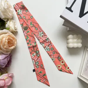 Close-up of floral print skinny silk scarf with orange-pink base and green leaf details