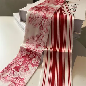 Close-up of red Toile de Jouy print and striped silk twilly scarves on a white book
