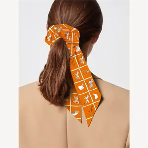 Chouchou ruban en soie orange au motif équestre porté par un modèle féminin