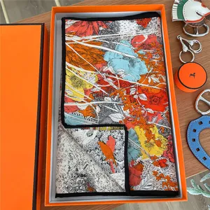 Floral print silk scarf with bird pattern in a classic orange gift box on wood