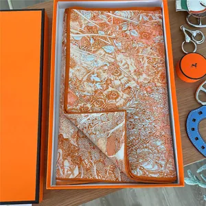 Detailed view of printed silk scarf folded in a premium orange gift box set