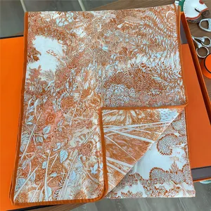 Detail of luxury silk scarf with intricate scenery prints on signature orange gift box