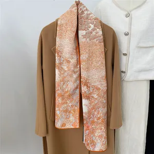 Detail of soft landscape print scarf with vibrant orange hand-rolled edges and texture