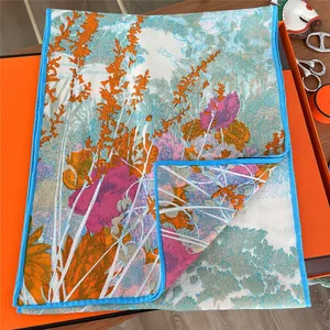 Detail of vibrant floral print scarf with silk texture and sky blue hand-rolled edges