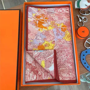 Detailed view of luxury silk scarf with floral patterns inside an orange gift box