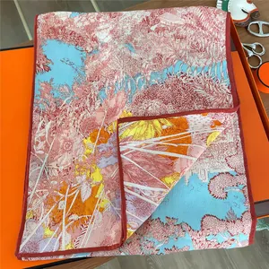 Close-up of landscape print scarf folded in an orange gift box on a wooden desk