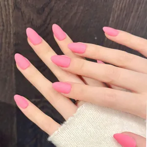 Close-up of matte neon pink almond nails on hand with white knit sweater background