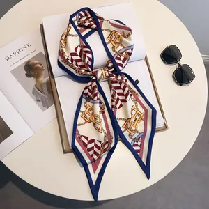 Elegant silk scarf with red white stripes and gold chain print tied in a bow on a table