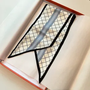 Close-up of narrow silk twilly scarf with black diamond pattern in orange gift box