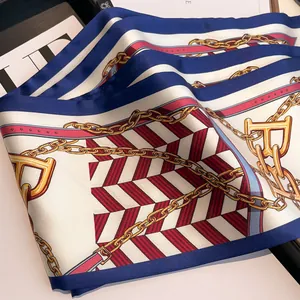 Elegant silk-feel long scarf with navy blue chain and belt patterns on a magazine