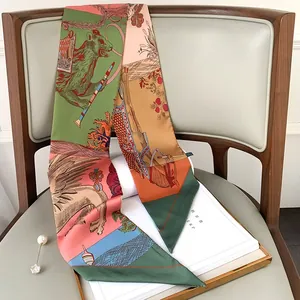 Elegant narrow silk scarf with floral patterns draped on a wooden chair with pearl brooch