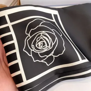 Elegant black silk scarf featuring white rose patterns and geometric borders for women