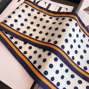 Navy blue polka dot silk scarf with orange contrast border on a fashion magazine