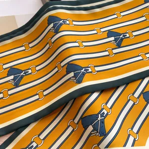 Detail of orange silk scarf with equestrian belt patterns and green hem borders