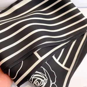 Close-up of black and white striped silk scarf featuring elegant rose outline patterns