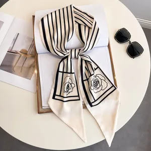 Elegant black and white striped silk scarf with rose pattern on white desk with magazine