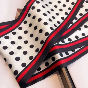 Macro detail of silk-like polka dot scarf featuring red and black stripe edge borders