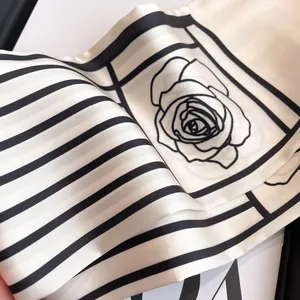 Close-up of black and white silk scarf with elegant floral patterns and fine stripes