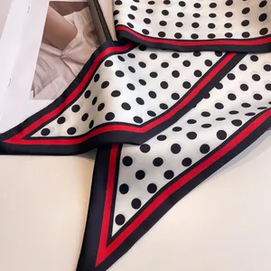 Macro detail of silk-like polka dot scarf with contrasting red and black striped borders