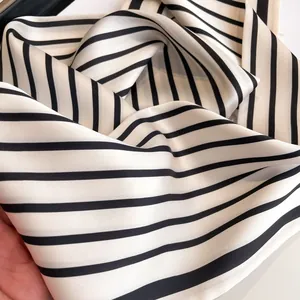 Close-up of silky black and white striped scarf showing premium texture and soft drapes