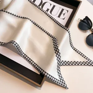 Detail of white satin silk scarf with black and white houndstooth border and chic pattern
