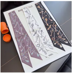 Detalle de tres elegantes pañuelos twilly de seda con motivos de llaves para bolsos