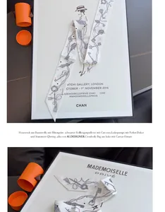 Detalle de un pañuelo twilly de seda con diseño retro y caja de regalo naranja de lujo