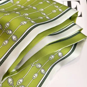Elegant green silk scarf with white leaf patterns and a glossy satin finish texture