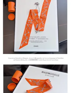 Detalle de un pañuelo twilly de seda naranja con motivos de llaves azules y cajas redondas