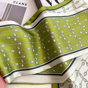 Grass green silk skinny scarf with floral pattern and white borders on a magazine