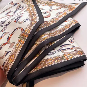 Close-up of silk scarf showing ivory satin texture with orange and blue art patterns