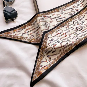 Detailed view of luxury silk twilly scarf with golden chain and letter prints