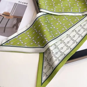Elegant green and beige floral silk scarf used as a versatile headband or bag ribbon