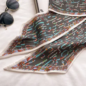 Detail of grey silk twilly scarf with baroque floral patterns and abstract letters