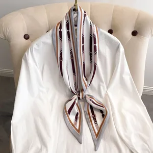 Foulard rayé style britannique bordeaux et crème drapé sur une chemise blanche