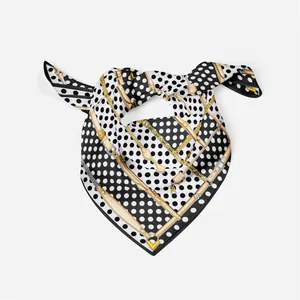Detail of silk scarf featuring polka dots, chain prints, and a gold V pendant