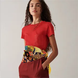 Detail of vibrant printed silk scarf tied around a red shirt pocket with embossed logo