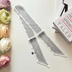 Silver-gray silk twilly ribbon with 'Love Never Fails' text for handbag handle decoration