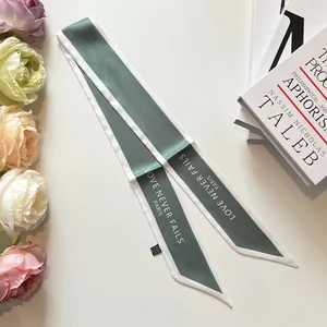 Detail of a dusty green silk scarf with white borders and Paris text inscription