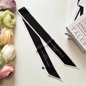 Elegant black and white twilly silk scarf with LOVE NEVER FAILS PARIS text on white background