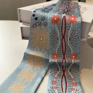 Détail d'un foulard en soie bleu clair avec tournesols jaunes sur boîtes cadeaux