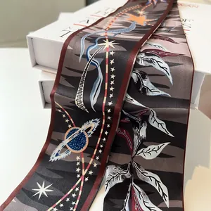 Close-up of narrow silk twilly scarf with celestial star and plant leaf pattern