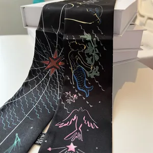 Detail of black silk twilly scarf with colorful mermaid and celestial star patterns