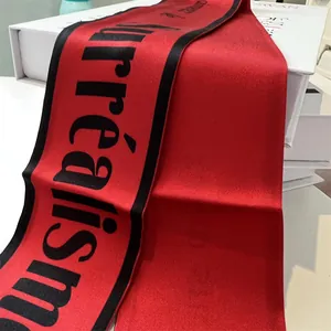 Dettaglio della sciarpa di raso rosso con stampa nera Surréalisme e trama in tessuto twill